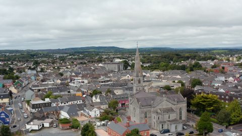 Aerial footage of Cathedral of Saints Peter and Paul and town in background. Old stone religious building with tall spire. Ennis, Ireland