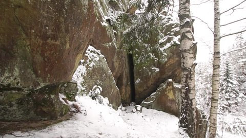 Ancient Rocks with a cleft in a stone in winter with a birch trees pedestal