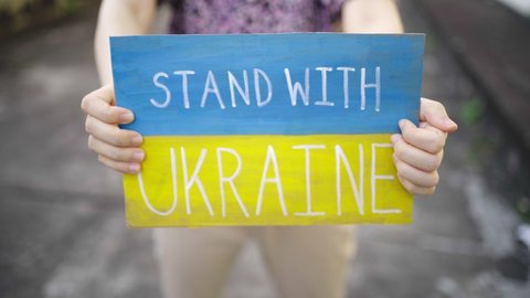 Demonstrator holding "Stand with Ukraine" placard