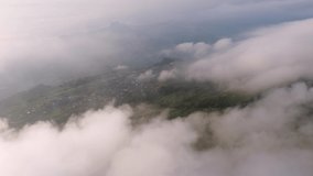 Beautiful 4K nature video footage of aerial view from drone flying forward of clouds and mist flowing on the mountains,winding road,village and rural area. Fog and cloud inversion over the mountains.