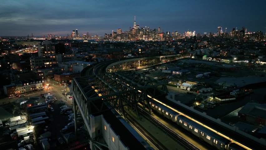 dusk aerial shot following elevated train towards NYC skyline Royalty-Free Stock Footage #1087581692