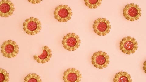 6k Creative pattern made of biscuit cookies with orange glaze appear from the center on bright pastel orange background. Stop motion flat lay	