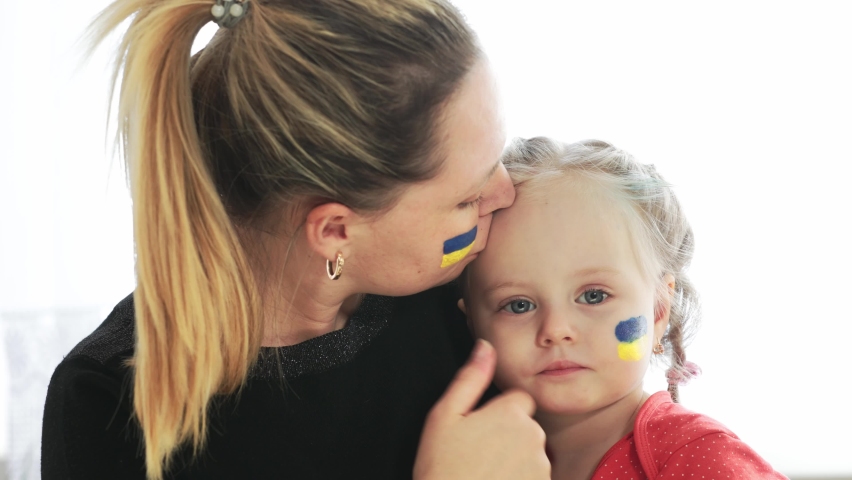 Ukrainian young mother with daughter with flag on the face with fear suffering and praying peace during war conflict between Russia and Ukraine, invasion of Russia in Ukraine | Shutterstock HD Video #1087583822