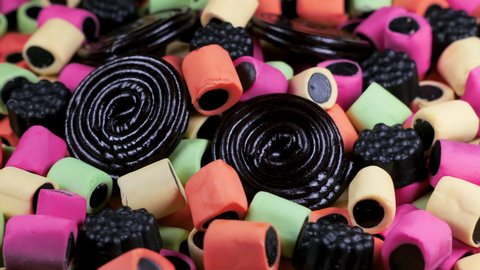 Macro view with rotation of licorice gummy candies. Colorful chewy sweets. Candy texture pattern close up.