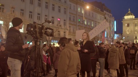 Female television journalist is reporting in front of a TV camera during a protest against Russia's invasion of Ukraine. Breaking news. 24.02.2022 Vaclavske nam,, Prague, CZ 