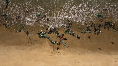 Vietnam tropical beach filled with plastic fishing net washed out after typhoon during monsoon season, consequence of climate change disasters and displacement, aerial ocean view