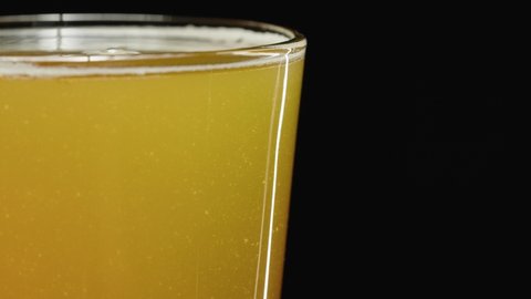 beer in a cold glass showing the sediment in a hazy ipa craft brew, side view black background