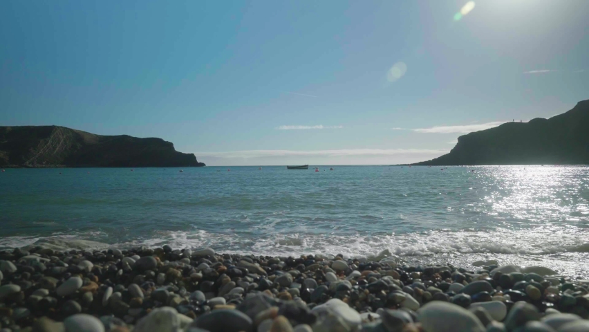 4K Cinematic landscape shot of the beach of Lulworth Cove, Dorset on a sunny day.