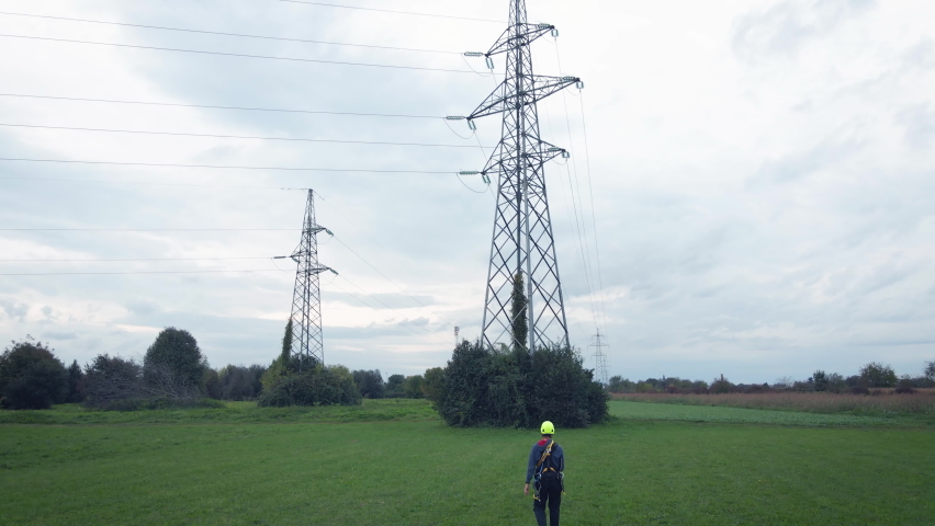 Engineer walking towards a Electric pylon with increasing price charts - 3D render Royalty-Free Stock Footage #1087602023