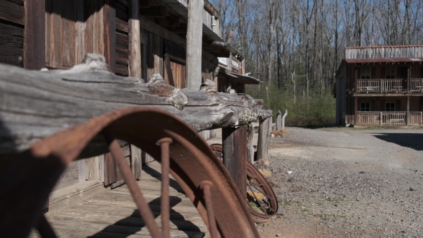 Old Western town store fronts, tight shot on wagon wheel