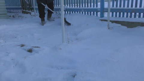 man removes snow from the street with a shovel