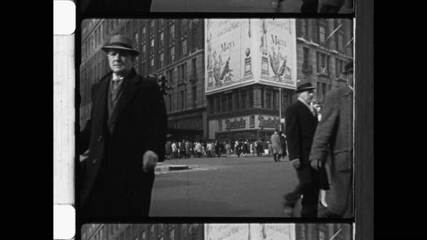 1940s New York City. Pedestrians and holiday shoppers cross busy intersection in front of Macy's Building. Vintage Automobiles fill intersection.  4K Overscan of Archival 16mm Newsreel.