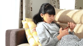 Elementary school girl looking at a smartphone in the living room