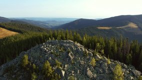 Fantastic aerial footage of a mountain rock covered with coniferous forest. Bird's eye view. Carpathian National Park, Ukraine, Europe. Cinematic drone shot. Filmed in UHD 4k video. Beauty earth.