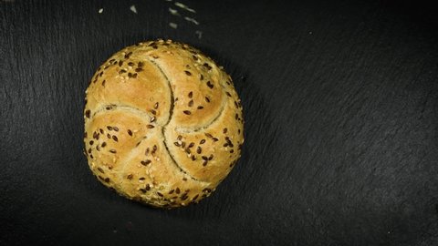Bread with seeds. Seven-grain bread, round bun with rye, wheat, barley grains, flaxseed, sesame and sunflower seeds, soy. Healthy food. Flour of all parts of cereals vegan. Black background trend food