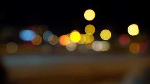 Bokeh in dark blurry background at night. The round colourful bokeh shine from car lights in city street. Abstract concept.