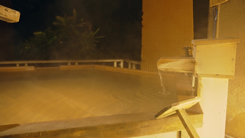 Night view of Japanese wooden open-air bath. Onsen.