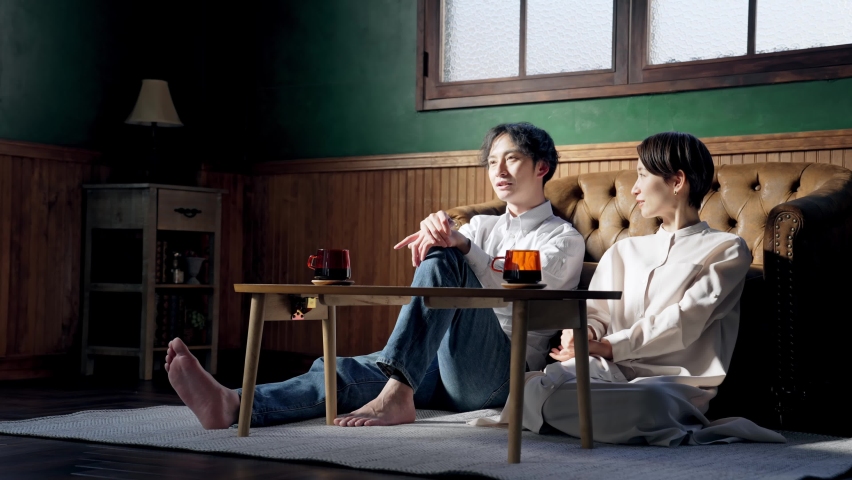 Asian couple watching TV in the room.