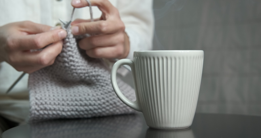 Mature female with knitting. A view of mature proffesional female hands with yarn knitting in the room.