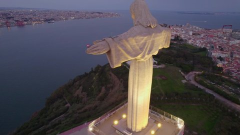 drone flying around a famous landmark in Lisbon, statue of Jesus Christ overlooking Tagus river and bridge with night lights. High quality 4k footage