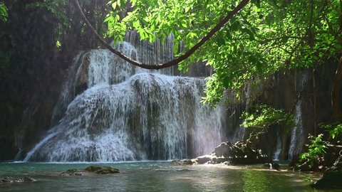 Beautiful Waterfall In Tropical Rain Forest. And stream in the natural park. This video is about Waterfall, nature, mountains, rocks, plants, trees, spring, and summer season with background.