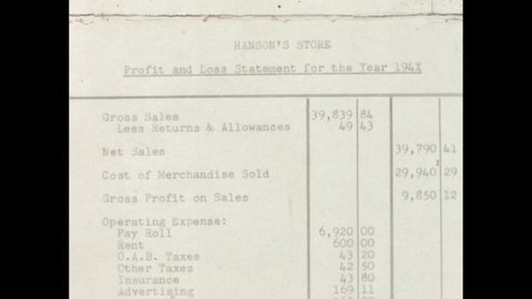 1940s: Finger showing the profit and loss document. Man sitting at desk in stockroom.