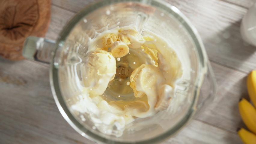 Vanilla Ice Cream and Banana Milkshake Mixed in High-Speed Blender in Slow Motion - Top View, Camera Moves Out Royalty-Free Stock Footage #1087625474