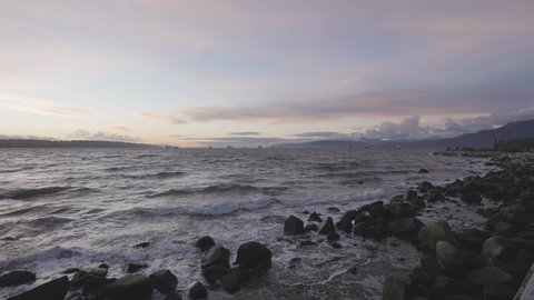 Panoramic View of Rocky shore at Seawall in Downtown Vancouver, British Columbia, Canada. Colorful Winter Sunset. Modern City on the Pacific Ocean West Coast. Slow Motion