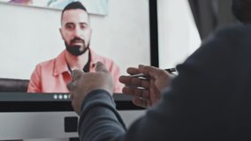 Close up shot of hands of businessman having discussion with male coworker via online video call on computer