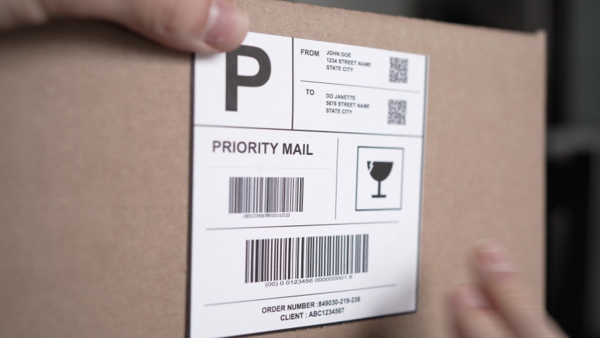 Hand applying a shipping label on the side of a cardboard box ready to be shipped. Royalty-Free Stock Footage #1087633244