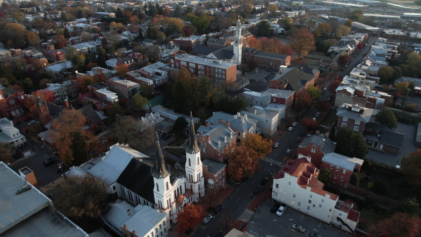 Aerial View of Downtown Frederick City, Maryland USA, Towers of Evangelical Lutheran and St John Evangelist Roman Catholic Church on Sunny Autumn Morning, Drone Shot