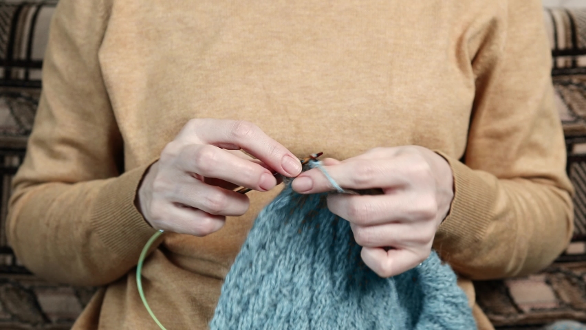 Closeup woman hands knitting wool scarf. Shallow focus.