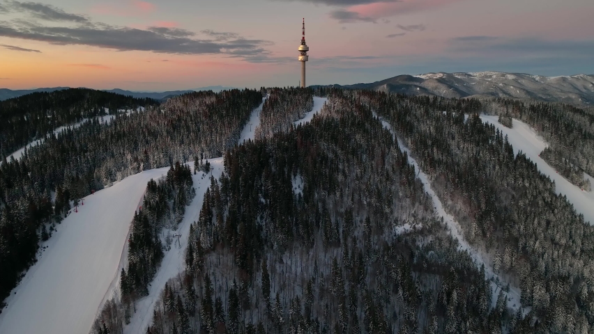 4K Aerial winter sunrise or sunset view of Rhodope Mountains and Snezhanka tower near resort of Pamporovo, Smolyan Region, Bulgaria