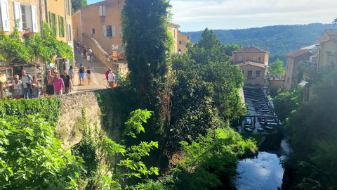 Moustiers-Sainte-Marie, France - August 2021 : People walking by the banks of the Riou river in the old streets of the village of Moustier Sainte Marie