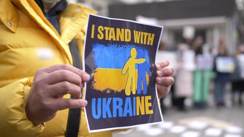 Hands holding a banner with the slogan "I stand with Ukraine" at an anti-war protest.