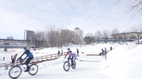 Winnipeg, Manitoba - Canada - February 27, 2022: People Walking and Cycling Along Frozen River. Sunny Winter Day in Winnipeg.