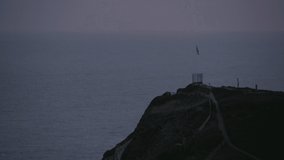 British flag flies on rocky outcrop above sea at sunset - Powered by Shutterstock - Get 15% off with code: PIKWIZARD15