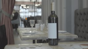 White wine in a bottle in a restaurant video footage. the hand of the waiter puts a glass of wine on the table in the restaurant. sommelier, alcohol. Close-up.