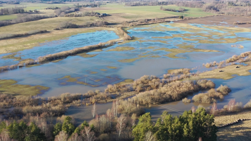 Aerial shot flying over and tilting down on flooded fields and meadows