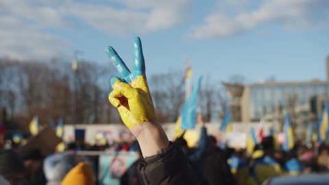 WARSAW, POLAND - FEBRUARY 27 2022: Hand In The Colors Of The Flag Of Ukraine Showing A Victory Gesture, Demonstration, Protest Against The Russian War Invasion In Ukraine. Ukrainian Flag, Protesters