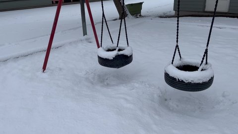 Swings moving slowly. Snow covered during the winter. White snowy ground. Cold weather. Stockholm, Sweden, Europe.