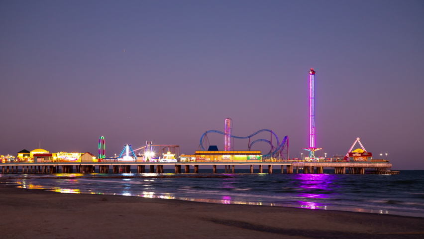 Generic Galveston TX Island Texas Night Timelapse at Beach with Theme Park on Pier with Lights Flashing and Reflecting on sea Water during Dusk on the Gulf of Mexico