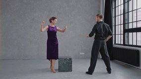 Man teaching woman dancing tango in grey studio against large windows. People practicing dancing romantic dance. Slow motion dancing tango. High quality 4k footage - Powered by Shutterstock - Get 15% off with code: PIKWIZARD15
