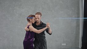 Man and woman are dancing a tango in gray room with large windows. People face to face dancing romantic dance. Slow motion dancing tango. High quality 4k footage - Powered by Shutterstock - Get 15% off with code: PIKWIZARD15