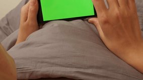 Female scrolling through greenscreen pages on smart phone display 4K 2160p UltraHD footage - Woman in bed relaxing while surfing on internet green screen display 4K 3840X2160 UHD video