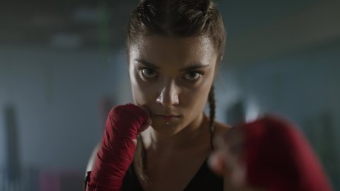 Woman power, portrait of a female fighter stands in a combat stance and looks into the camera, a serious look, 4k slow motion.