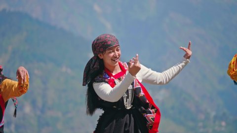 Young beautiful cheerful Indian Asian Woman or female wearing traditional attire dancing outdoors with a background of Mountainous valley in daylight. Concept of customs, music, culture, traditions