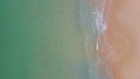Aerial view of turquoise ocean wave reaching the coastline. Beautiful tropical sand beach from top view. Andaman sea in Thailand. Summer holiday vacation concept. 4K drone video