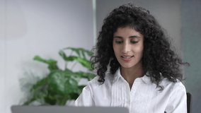 Close up of young indian woman applicant talks with employer pass job interview by video call. Asian girl looks at laptop screen speaking with colleague or client working remotely from office.