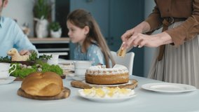 Unrecognizable woman cutting easter cake and passes a piece to the family in the background. Shot with RED helium camera in 8K. 